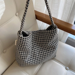 Close-up of black and white houndstooth woven texture and brand label on a shoulder bag