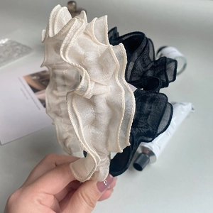 Close-up of beige and black chiffon headband featuring ruffled layered design