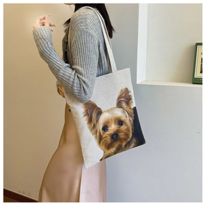 Detail view of the Yorkie print on a large canvas tote bag carried by a model