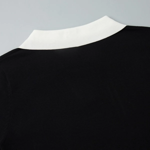 Détail du col polo blanc contrastant sur un pull en maille noire à manches courtes