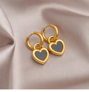 Macro detail of double-sided heart earrings with gold pleated texture on silk background