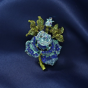 Macro detail of vintage blue rhinestone rose brooch on a luxurious silk background