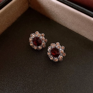 Close-up of vintage style floral earrings with red gemstone and champagne diamonds