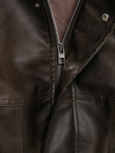 Dettaglio della zip argentata e del bottone a pressione su una giacca in pelle marrone