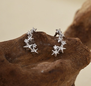 Macro shot of silver star cluster earrings with zircons on a natural wood surface