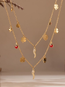 Gros plan détaillé d'un collier multi-rangs doré avec pendentifs piment et coccinelle