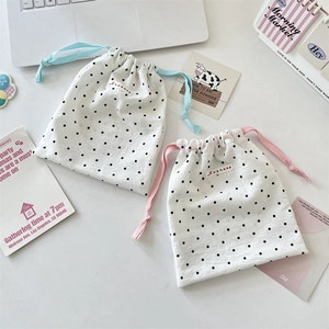 Close-up of polka dot drawstring storage bags in a cozy desk setting with red woven labels