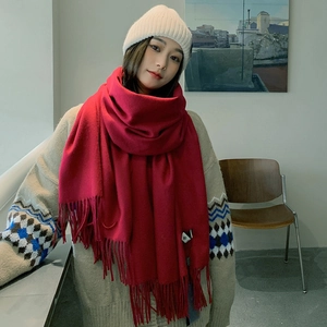 Detail of a bright red cashmere-like scarf with fringe, styled with a white knit beanie