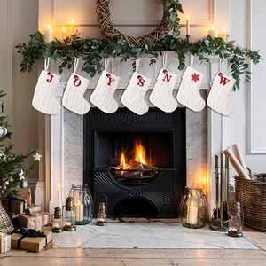 Close-up of white knitted Christmas stockings with red JOYSNOW letters on fireplace
