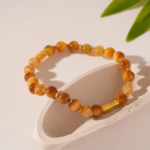 Detailed view of amber Tiger Eye beads and golden spacers on a white stone tray