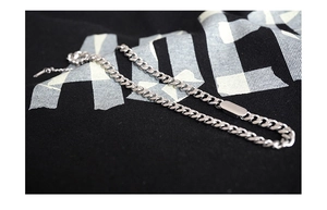 Detail of silver Cuban chain necklace with minimalist rectangular plate on black fabric