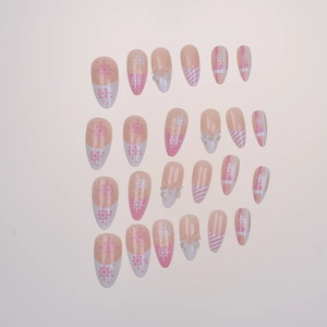 Detail of pink almond press-on nails with 3D resin bows and white snowflake patterns