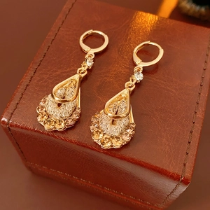 Close-up of vintage gold teardrop earrings with mesh design and champagne zircons