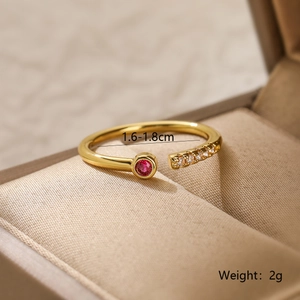 Detail of gold-plated ring with red zircon stone and side crystals in jewelry box