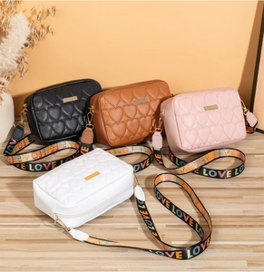 Detail of heart quilted crossbody bags with colorful LOVE print wide straps