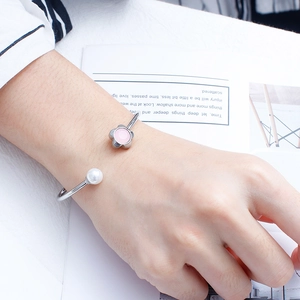 Detailed shot of a silver C-shaped cuff bracelet with pink flower and pearl accents