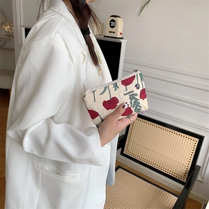Detail of fabric makeup bag with red poppy floral pattern and side brand label
