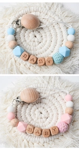 Detail of beech wood and silicone baby pacifier clips with BABY letter beads