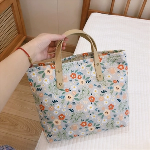 Detail of floral tote bag with daisy patterns, faux leather handles and rivet accents