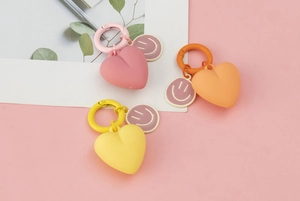 Detailed view of pink, orange, and yellow heart keychains with cute smiley charms