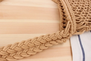 Detailed macro view of handmade macramé beach bag featuring woven handles and mesh patterns