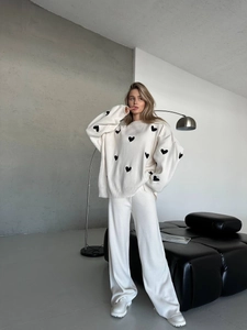 Dettaglio maglione oversize bianco in maglia con ricamo a cuore e pantaloni ampi coordinati