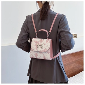 Detailed view of pink butterfly print backpack for women with metal bow on model's back
