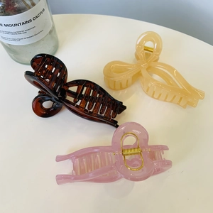 Detailed view of hair clips in amber, beige, and pink colors on a white surface