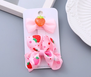 Detail of handmade pink strawberry bow hair clips set for girls on decorative tray