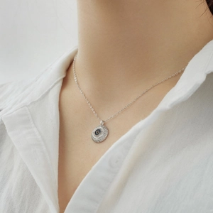 Detail of S925 sterling silver evil eye necklace with paved cubic zirconia on model