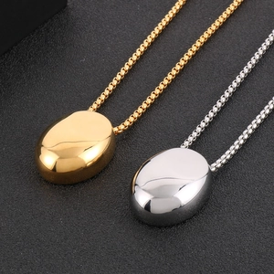 Close-up of gold and silver polished oval teardrop pendants on stainless steel box chains