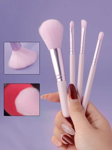 Detailed close-up of soft pink makeup brush bristles and ergonomic handles in hand