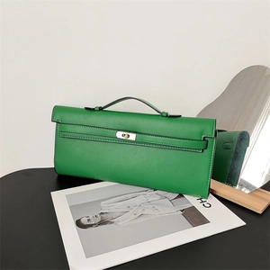 Elegant green leather handbag with metal turn-lock closure on a fashion magazine