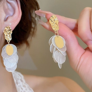 Vue détaillée de boucles d'oreilles dorées à pampilles de perles portées par un mannequin