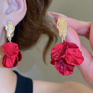Close-up of red acrylic petal tassel earrings with gold hammered metal top studs