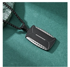 Detail of matte black dog tag pendant with tire tread edges and crystal inlay