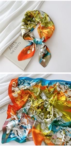 Detailed close-up of vibrant floral print silk scarf with fine edge stitching texture