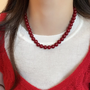 Macro shot of minimalist red glass beaded necklace on white and red knitwear