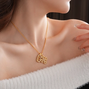 Primo piano di una collana dorata con ciondolo vajra incastonato di zirconi sul collo