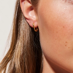 Close-up of 14K gold-plated U-shaped stainless steel earring worn on a model's ear