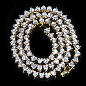 Close-up of golden heart-shaped tennis chain with sparkling cubic zirconia stones