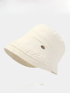 Close-up of cream bucket hat showing textured fabric surface and metal logo detail