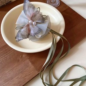 Detail of grey-purple butterfly hair claw with pearls and light green ribbon streamers