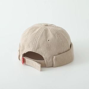 Detail of beige corduroy beanie with adjustable strap and small red tag for kids