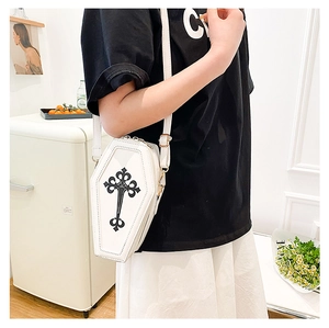 Close-up of a white coffin-shaped crossbody bag with a black gothic cross on the side