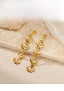 Detail of 18K gold plated celestial drop earrings on elegant marble and silk