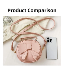 Pink mini round crossbody bag with bow detail shown next to a smartphone for size scale