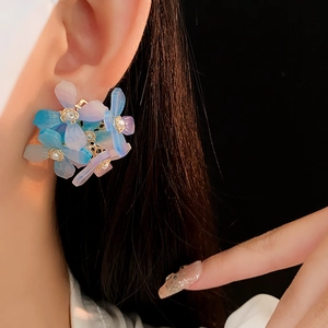 Gros plan d'un mannequin portant des boucles d'oreilles fleurs en acrylique bleu et violet