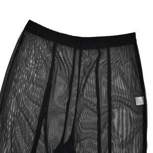 Détail de legging en maille noire transparente montrant la texture et l'étiquette d'entretien
