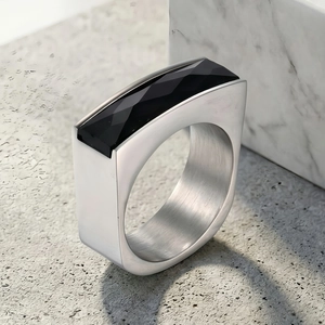 Macro shot of silver industrial ring with rectangular black faceted gemstone on stone